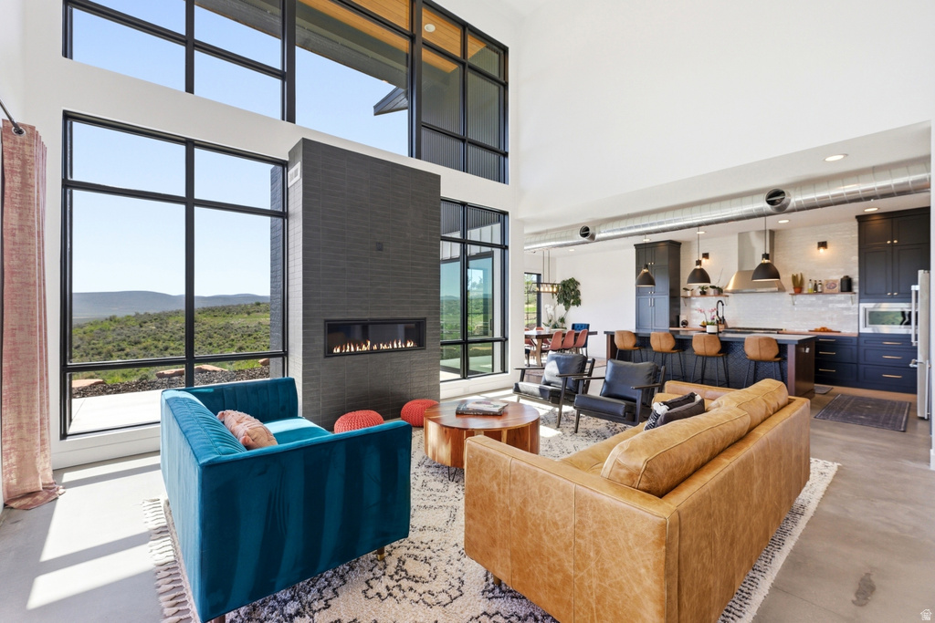 Living area featuring expansive black-framed windows, a floor-to-ceiling dark brick fireplace with an integrated linear firebox, and high ceilings