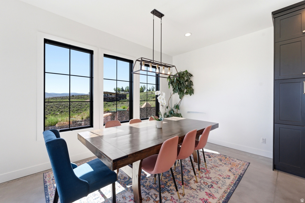 Dining area with expansive windows featuring black muntins, a linear chandelier, built-in dark cabinetry, and light-toned flooring