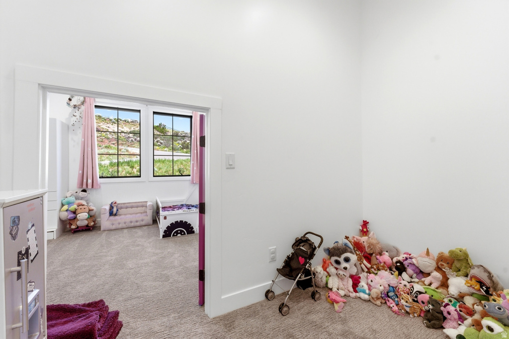 Carpeted room featuring a wide doorway opening into another carpeted room with multiple windows
