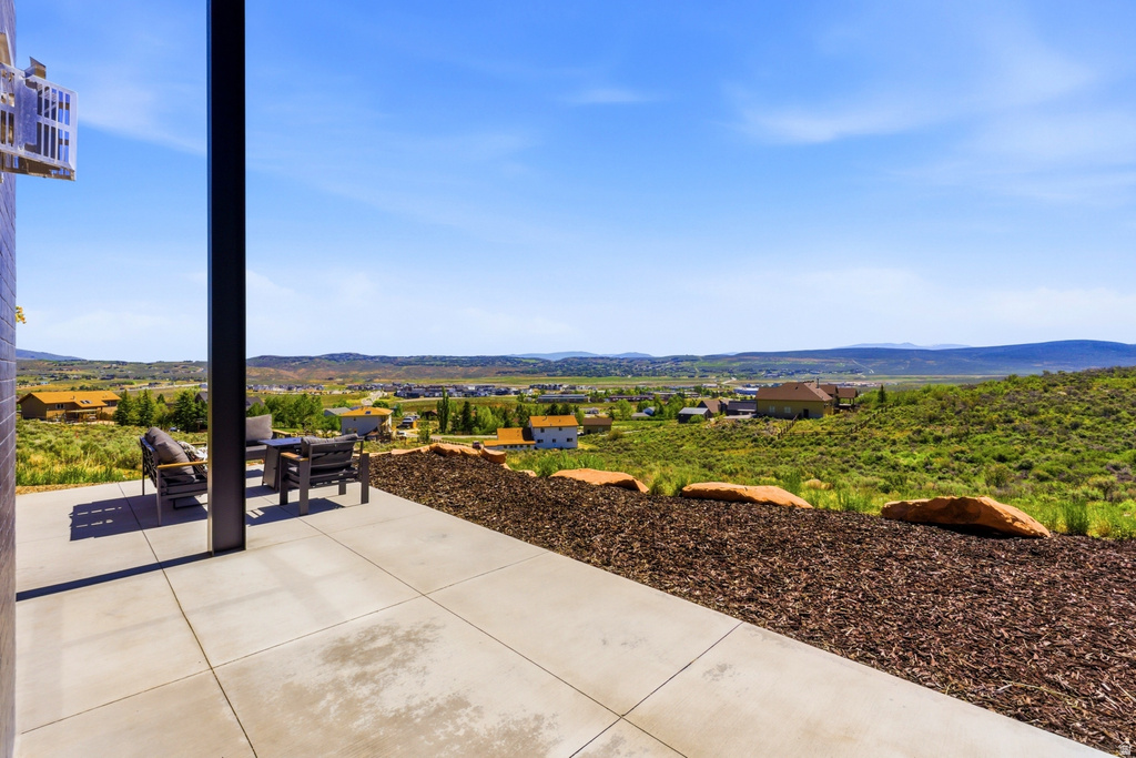 Expansive concrete patio with a dark support column, set against a backdrop of rolling hills and distant structures