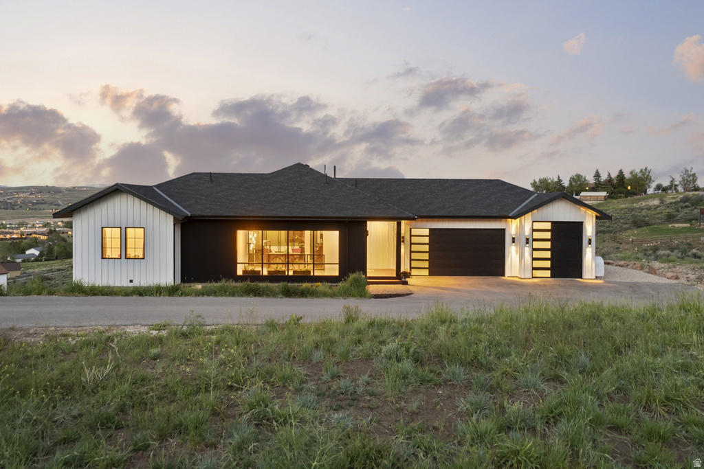 Contemporary ranch-style exterior featuring a black and white facade, board and batten siding, multiple garage doors with frosted glass panels, and a prominent picture window