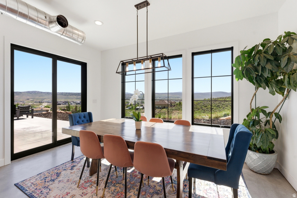 Dining area with expansive window wall, glass patio slider, and concrete-finish flooring