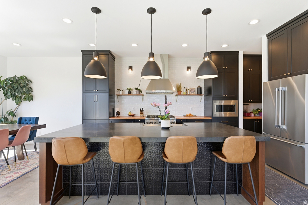 Spacious kitchen featuring a large island, dark cabinetry, stainless steel appliances, a tile backsplash, and recessed lighting