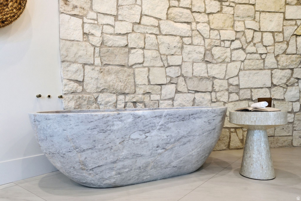 Freestanding stone bathtub with wall-mounted bronze fixtures