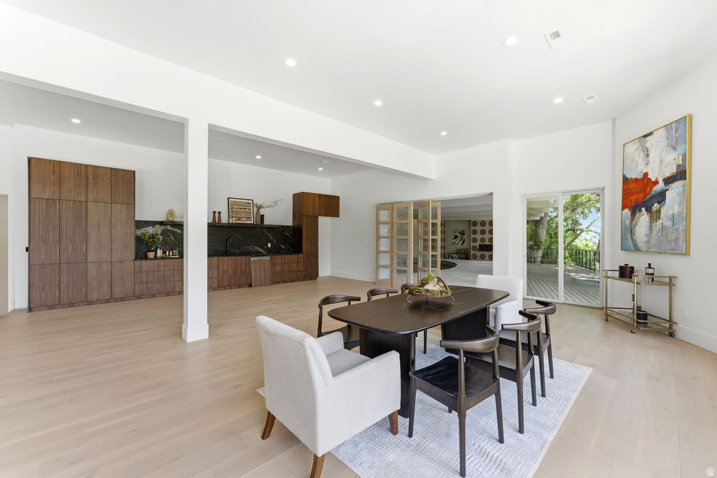 Spacious dining area featuring light wood-finish flooring, recessed lighting, and direct patio access