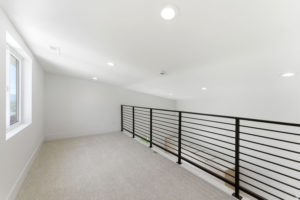 Upper level loft featuring a contemporary metal railing, recessed lighting, and a window providing natural light