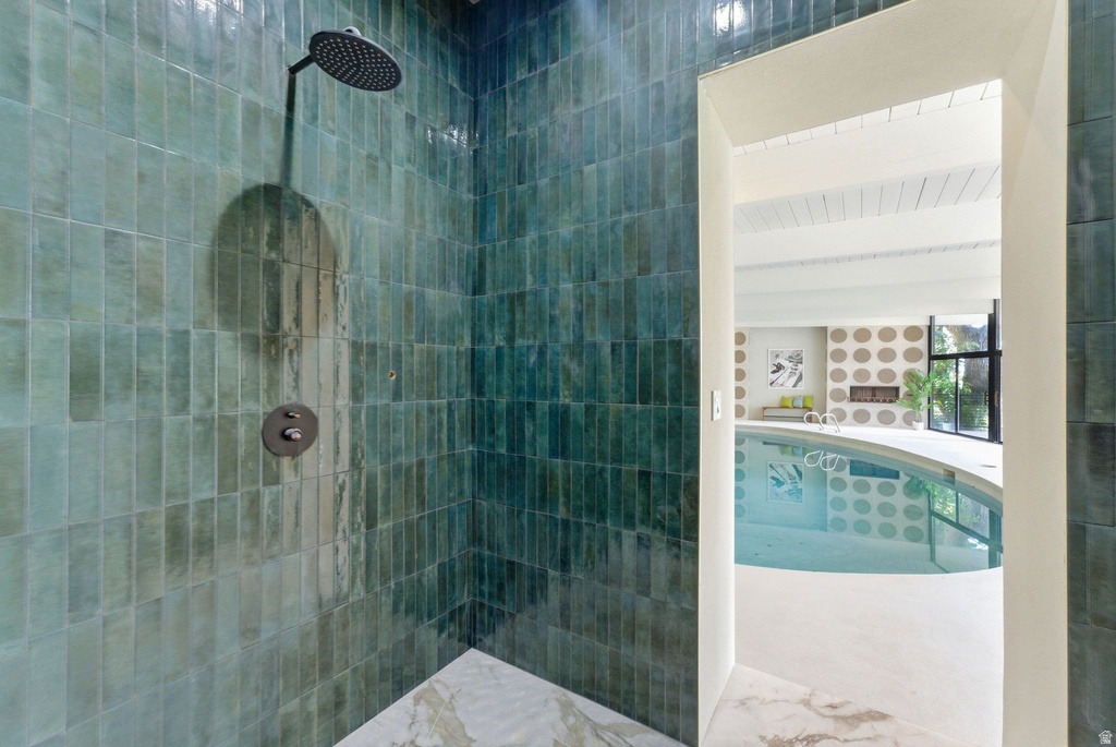 Walk-in shower with vertical teal-toned tilework and a rain showerhead