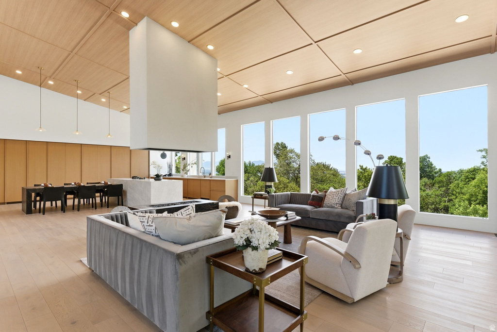 Open-concept living area featuring a central floating fireplace, wood-finish flooring, and a coffered wood ceiling