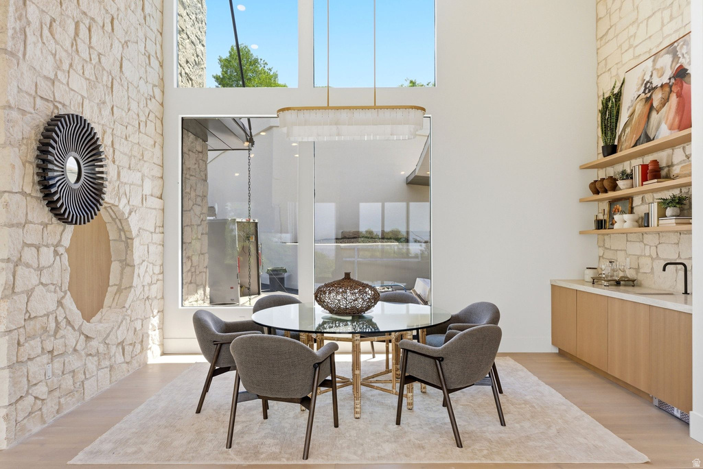 Expansive dining area featuring a stone accent wall, high ceilings with clerestory windows, and wood-finish flooring