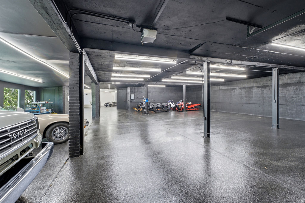 Spacious garage featuring a durable epoxy floor, exposed brick pillars, and ample fluorescent lighting