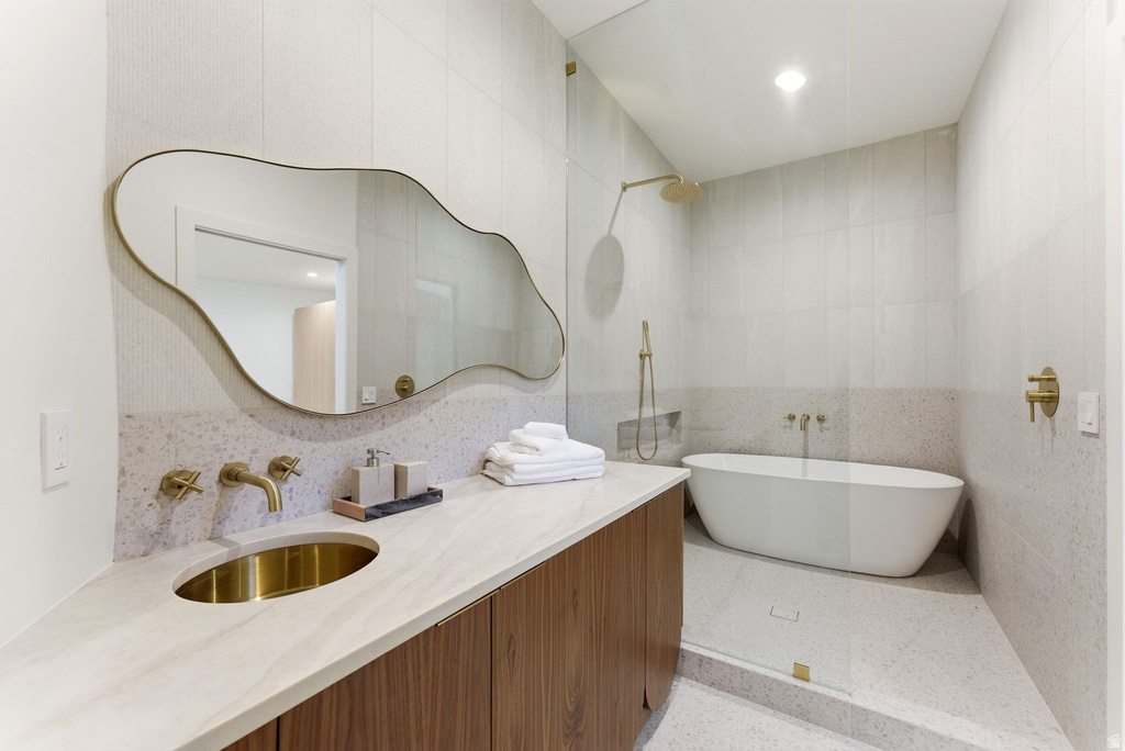 Contemporary bathroom with a freestanding tub, walk-in shower with glass enclosure, wood-finish vanity with an integrated basin, and gold-tone fixtures