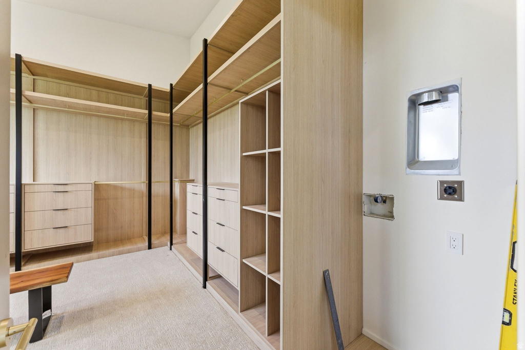 Custom closet system featuring light wood-finish shelving and drawer units, black metal supports, and integrated hanging rods