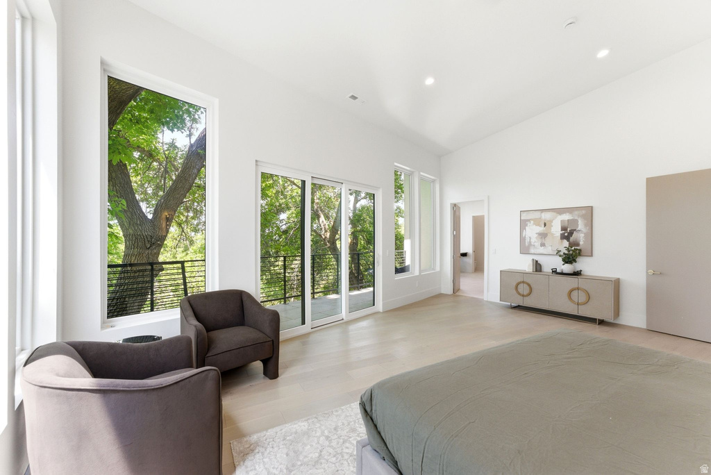 Spacious interior featuring expansive windows, sliding glass door balcony access, high vaulted ceilings, recessed lighting, and light wood-finish flooring