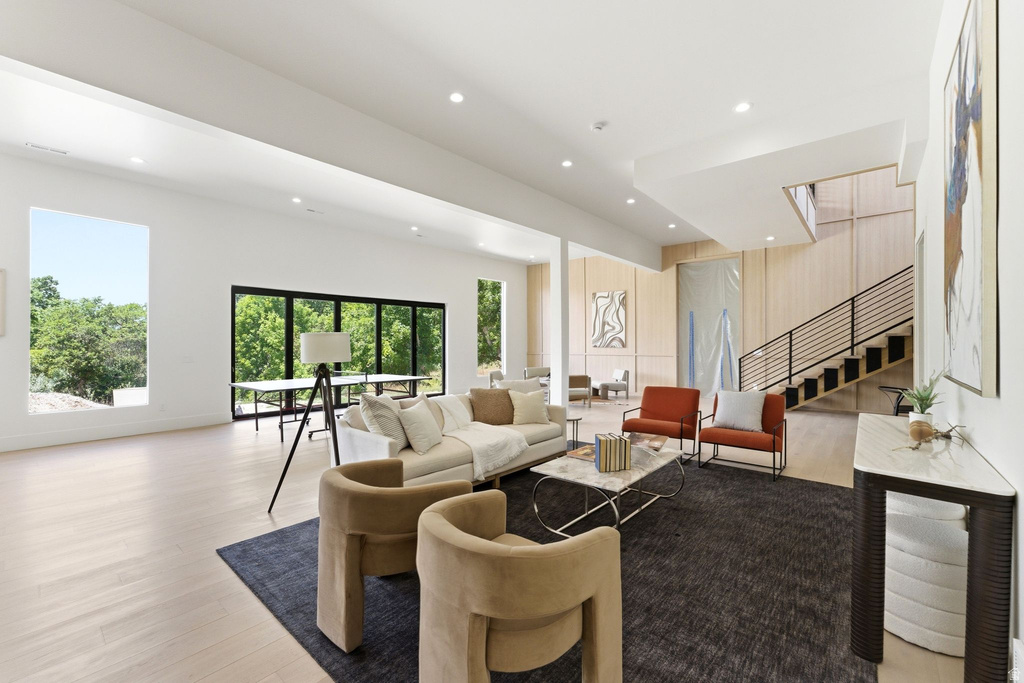 Spacious living area featuring light wood-finish flooring, recessed lighting, and large windows with black frames