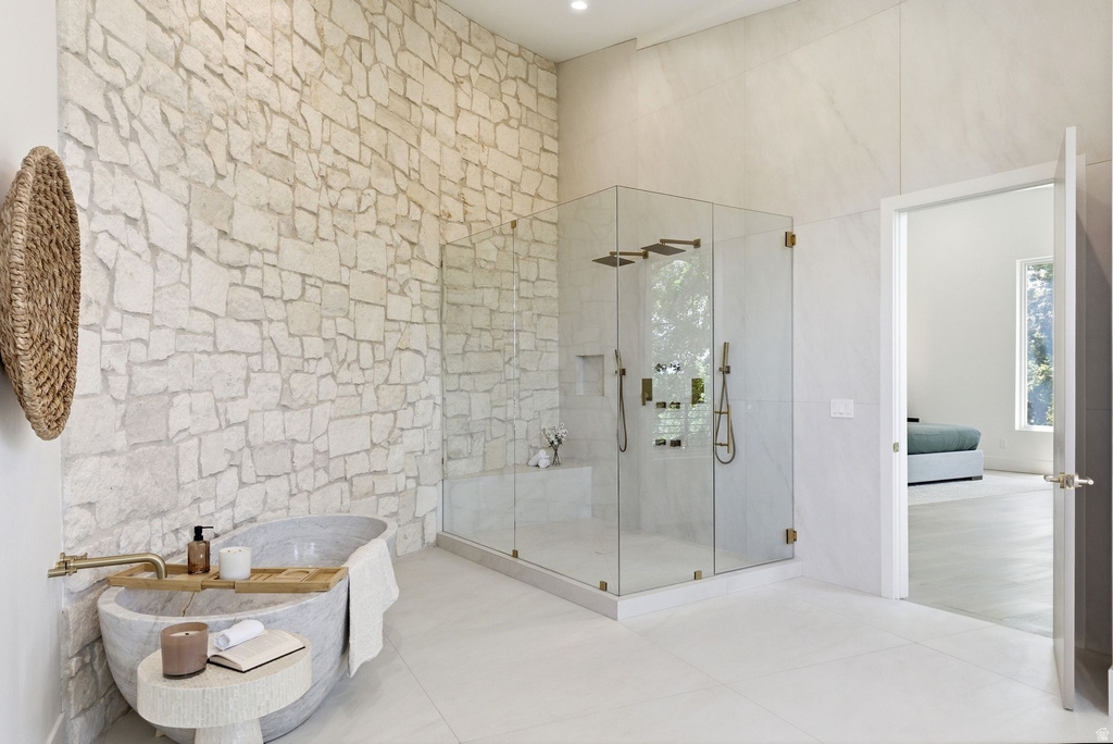 Spacious bathroom featuring a large stone accent wall and a freestanding soaking tub