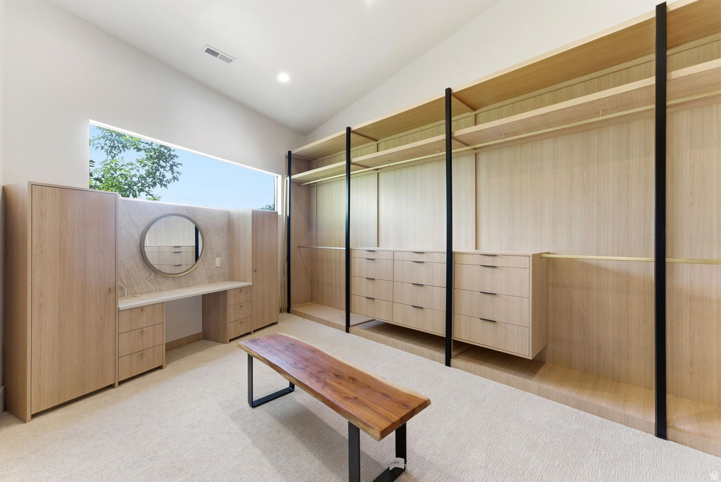 Custom built-in closet system featuring light wood-finish cabinetry and shelving, integrated drawers, and a dedicated vanity area with a circular mirror
