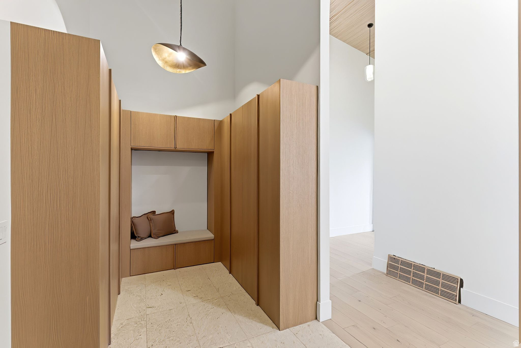 Entryway featuring custom built-in cabinetry with integrated bench seating, vaulted ceilings, and a distinctive pendant light fixture