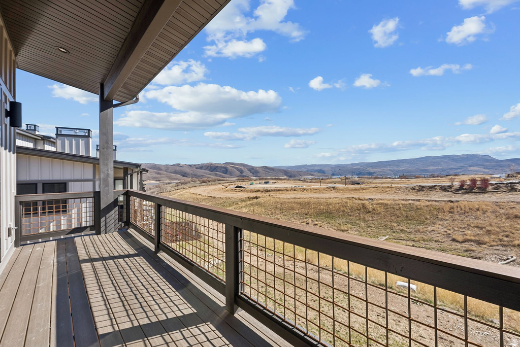 Expansive outdoor deck featuring wood-finish flooring and a contemporary metal grid railing