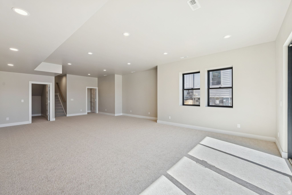 Expansive room featuring light-toned carpeting, recessed ceiling lighting, and a neutral wall color