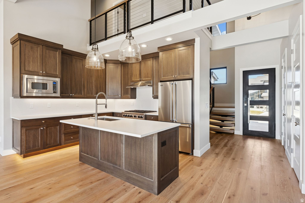 Contemporary kitchen featuring wood-finish cabinetry, stainless steel appliances, and a central island with a solid surface countertop