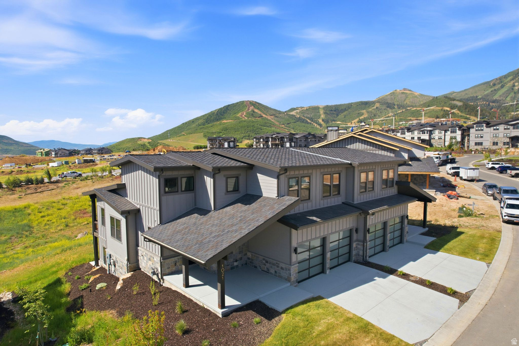 Modern multi-story property featuring a gray vertical siding exterior and stone accents