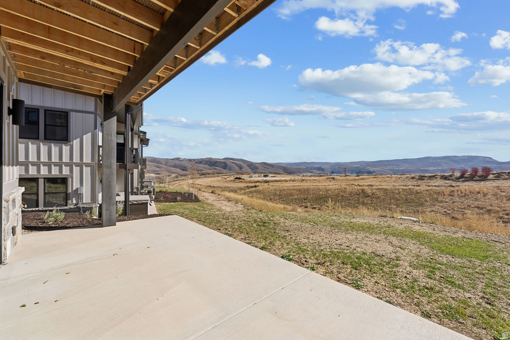 Expansive concrete patio with a wood-plank soffit and exposed beams, offering open-air outdoor space