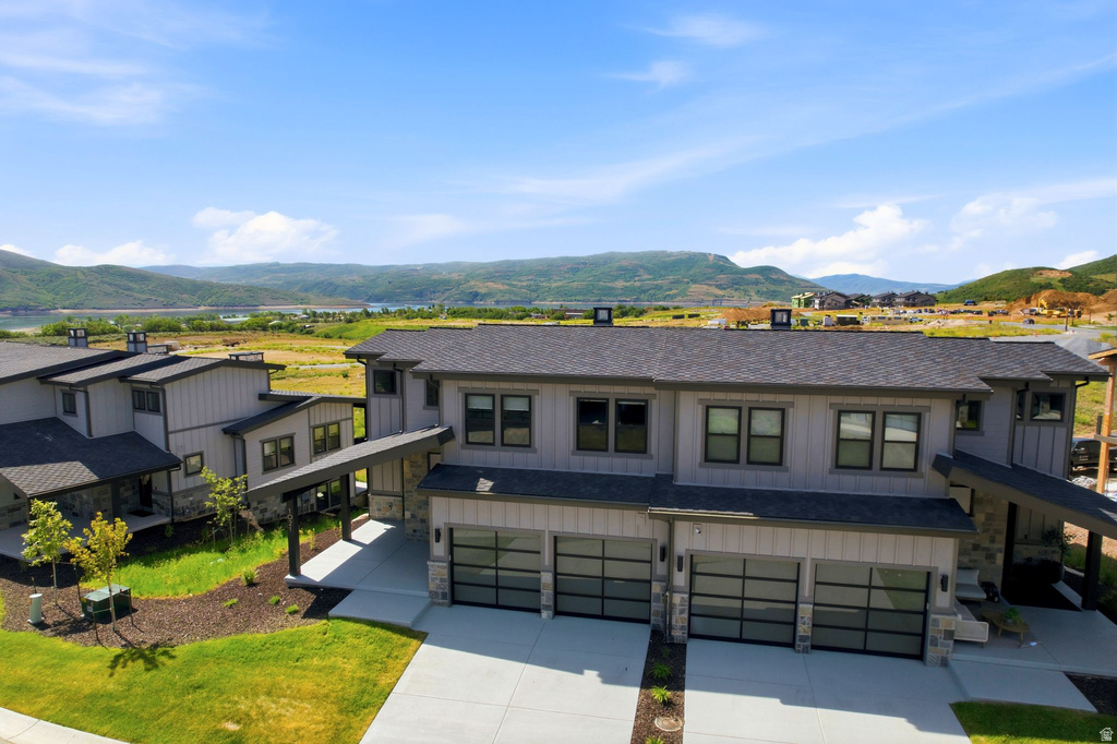 Modern residential structures featuring grey siding, dark roofs, and multiple garage doors with frosted glass panels