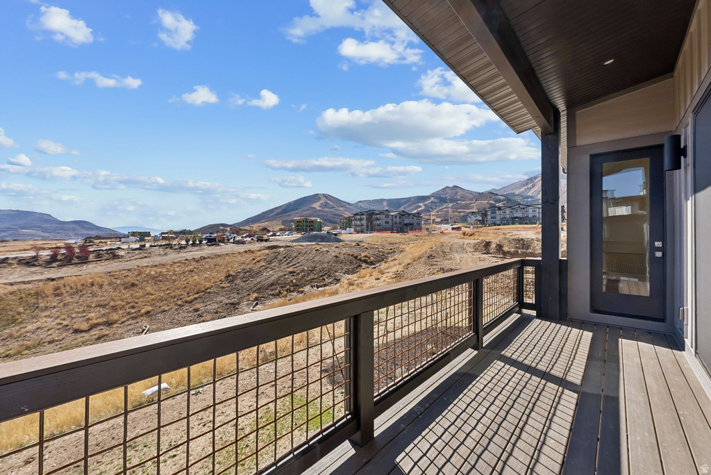Spacious outdoor balcony featuring composite decking, a durable metal grid railing, and an exterior door with a full-light glass insert