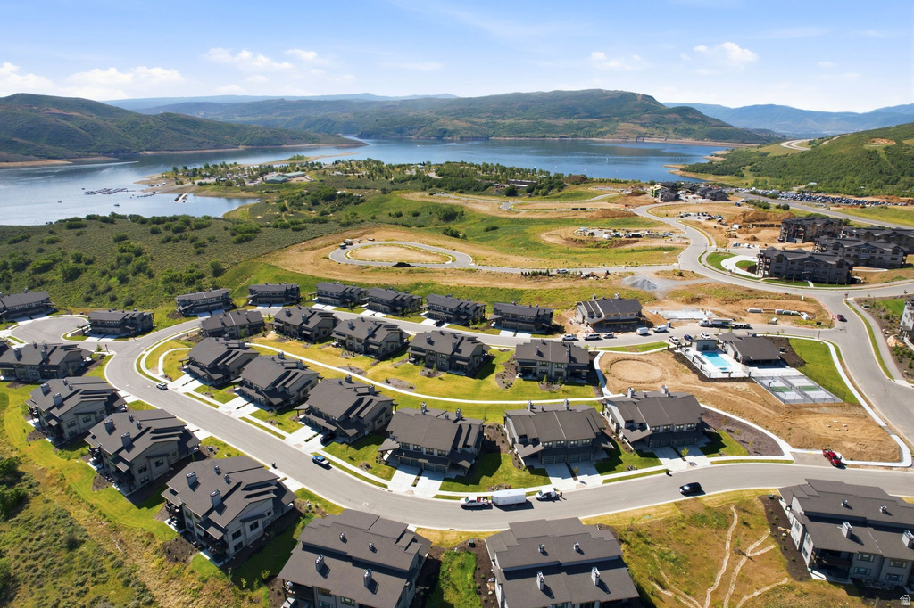 Modern residential development featuring multiple dark-roofed homes, paved roadways, and green landscaping