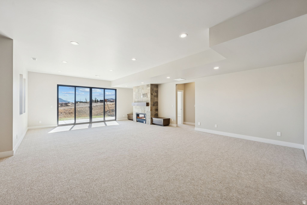 Spacious room featuring light-colored carpeting, recessed lighting, and a stone-clad fireplace