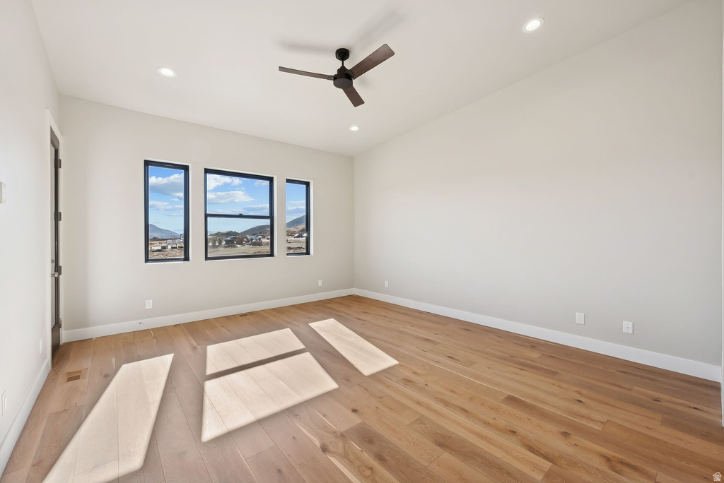 Spacious room featuring wood-finish flooring, recessed lighting, and a contemporary ceiling fan