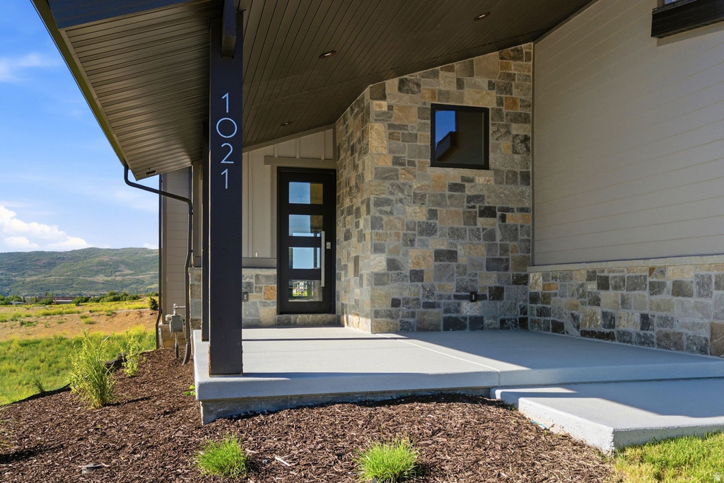 Modern entry featuring a prominent stone facade and a contemporary black door with multiple glass inserts