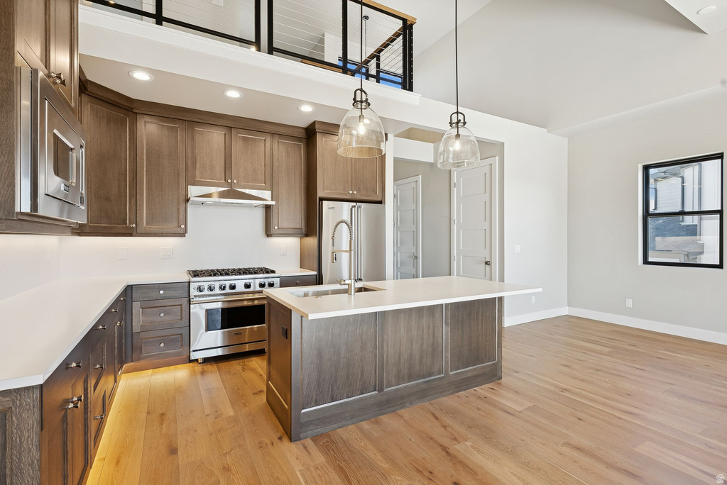 Open-concept kitchen featuring rich wood cabinetry, stainless steel appliances, and a central island with an undermount sink