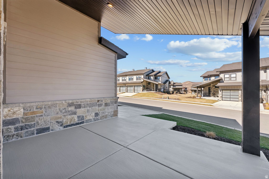 Covered porch with concrete flooring and a wood-slat ceiling, featuring a stone and siding exterior