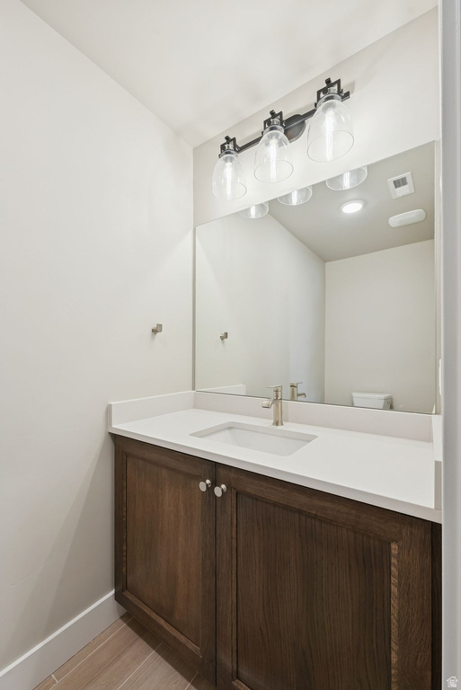 Vanity with wood-finish cabinetry, white countertop, and integrated sink