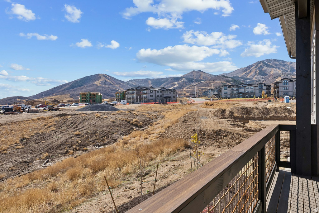 Balcony with wood-finish railing and metal mesh infill, overlooking a landscape with distant mountains