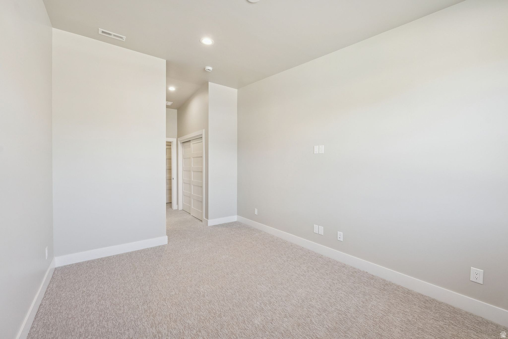 Spacious room featuring light-toned carpeting, white baseboards, and neutral wall paint