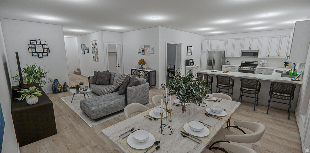 Open-concept living space featuring wood-finish flooring, a contemporary kitchen with white cabinetry, stainless steel appliances, and a substantial island with seating
