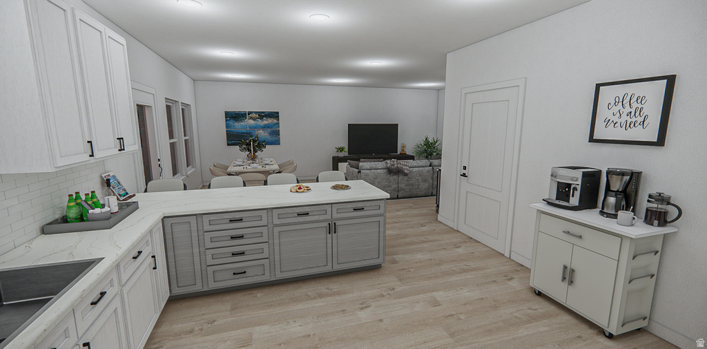 Open-concept kitchen featuring two-tone cabinetry, a central island with integrated storage, wood-finish flooring, and white countertops