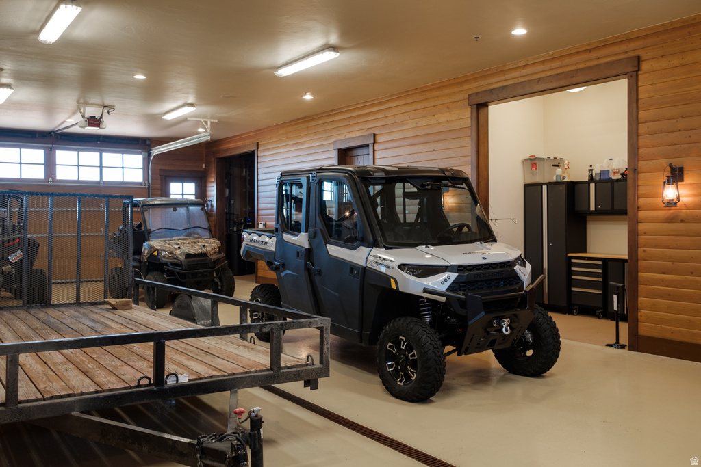 Spacious garage featuring light-toned flooring, wood-paneled walls, and overhead fluorescent lighting