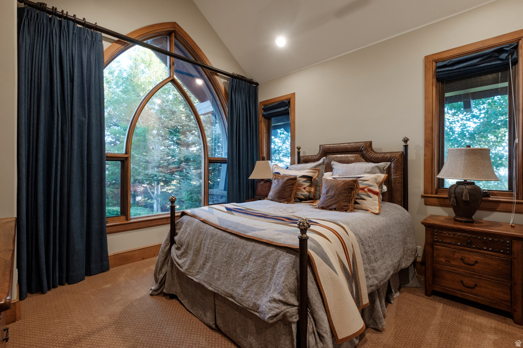 Vaulted ceiling room featuring a large arched window with wood framing, accompanied by two rectangular windows