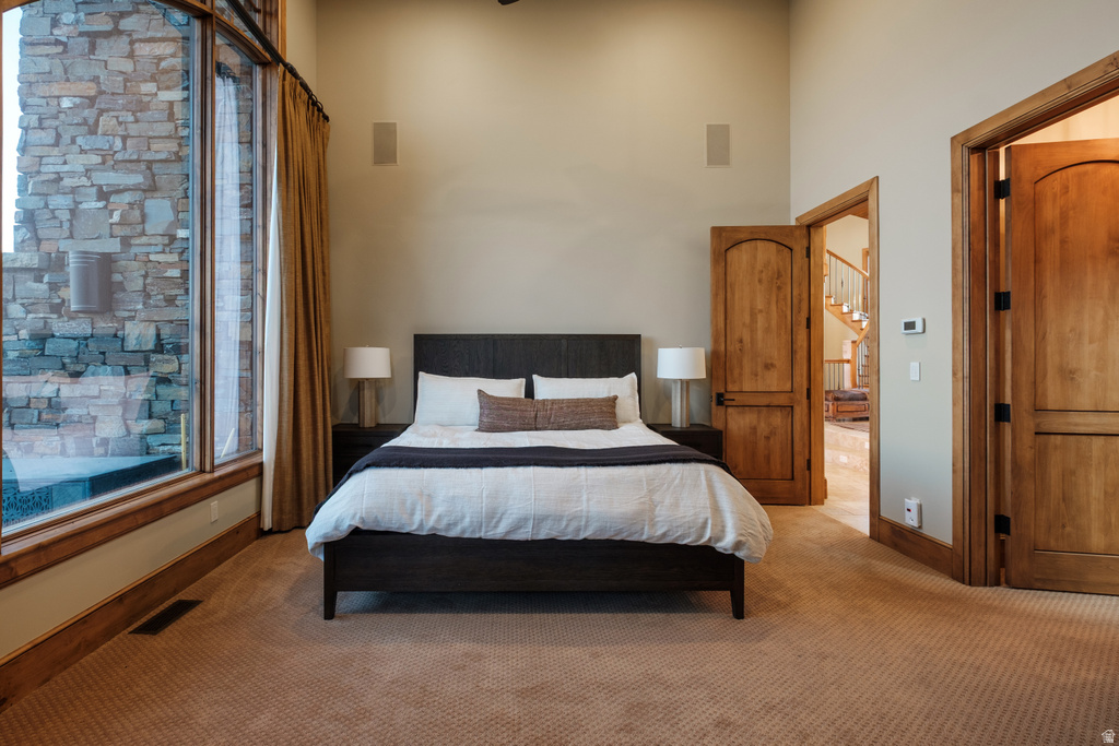 Spacious room featuring a bed with nightstands, large windows with natural wood trim, and two wood-paneled doors