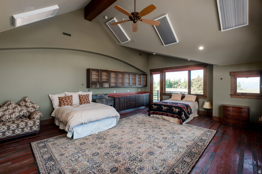 Spacious room featuring rich wood-finish flooring, a vaulted ceiling with skylights and a ceiling fan, and extensive built-in cabinetry with glass fronts