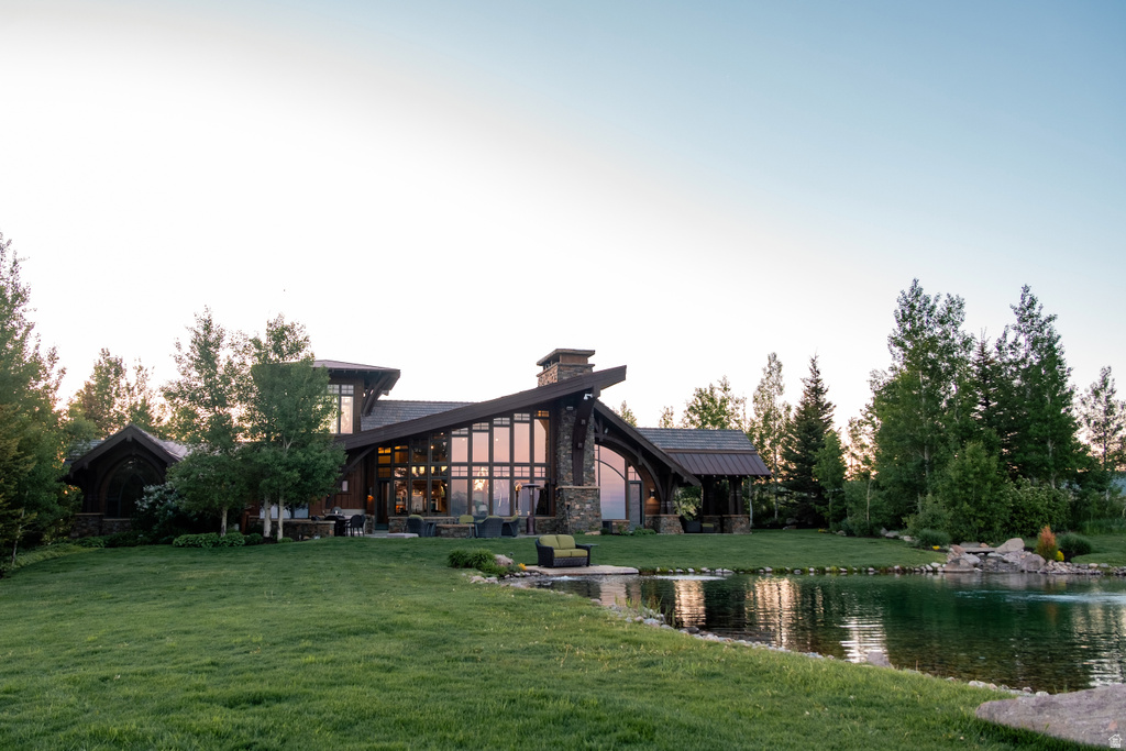 Modern architectural home featuring extensive glass paneling, a stone-clad chimney, and a multi-level roofline