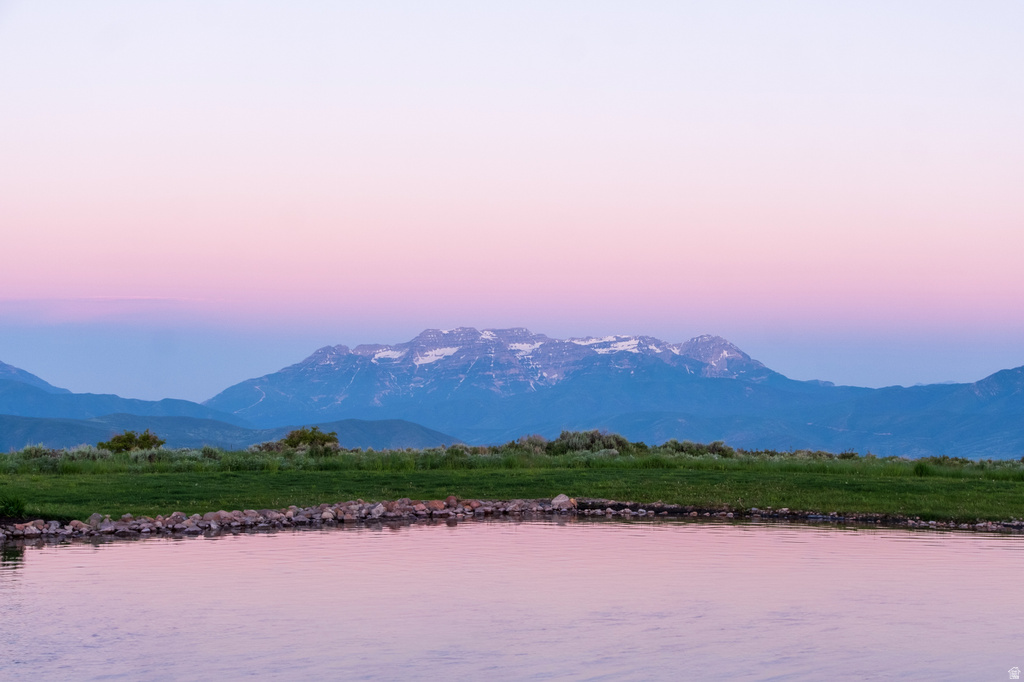 Body of water with a rocky bank and a distant mountain range featuring snow-capped peaks