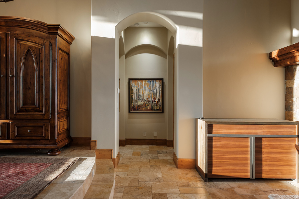 Arched hallway entrance with recessed lighting and natural stone flooring