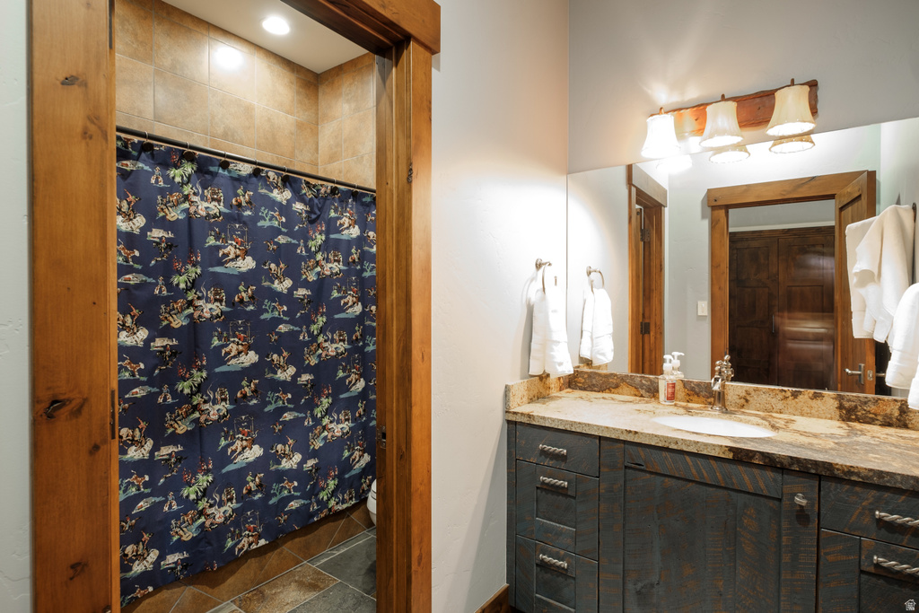 Bathroom featuring a single vanity with stone countertop, undermount sink, and wood-finish cabinetry