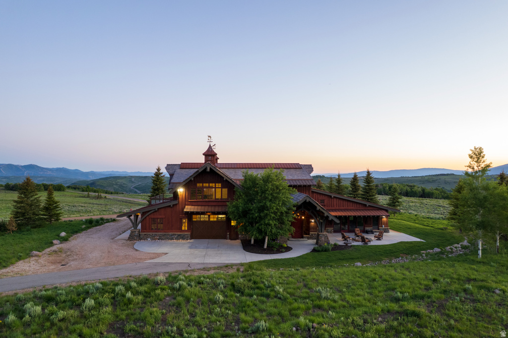 Rustic-inspired exterior featuring a cupola with a weathervane, a metal roof, wood siding, stone accents, and an attached garage
