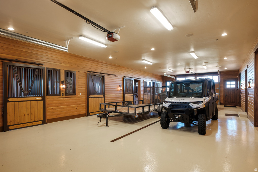 Spacious interior featuring wood paneling, multiple stall doors with metal grating, and recessed lighting