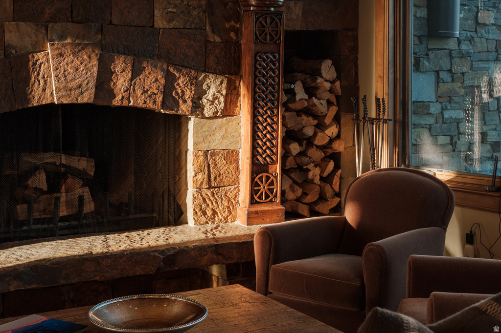 Stone fireplace with an arched opening and a stone hearth, featuring an ornate carved wood column and built-in wood storage